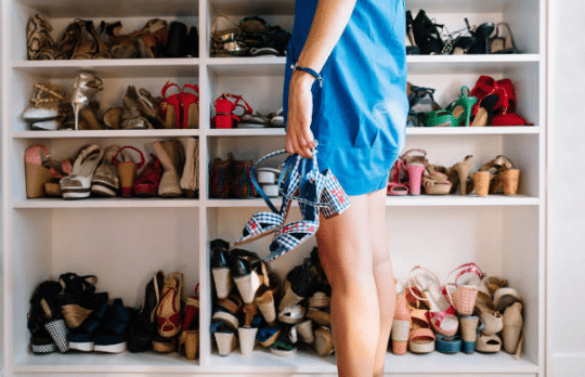 femme portant une robe bleue se tenant devant un placard rempli de chaussures