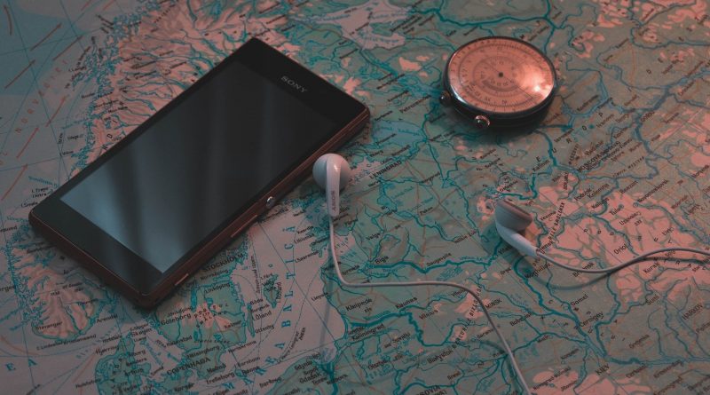 Téléphone posé sur une carte du monde avec des écouteurs et une boussole