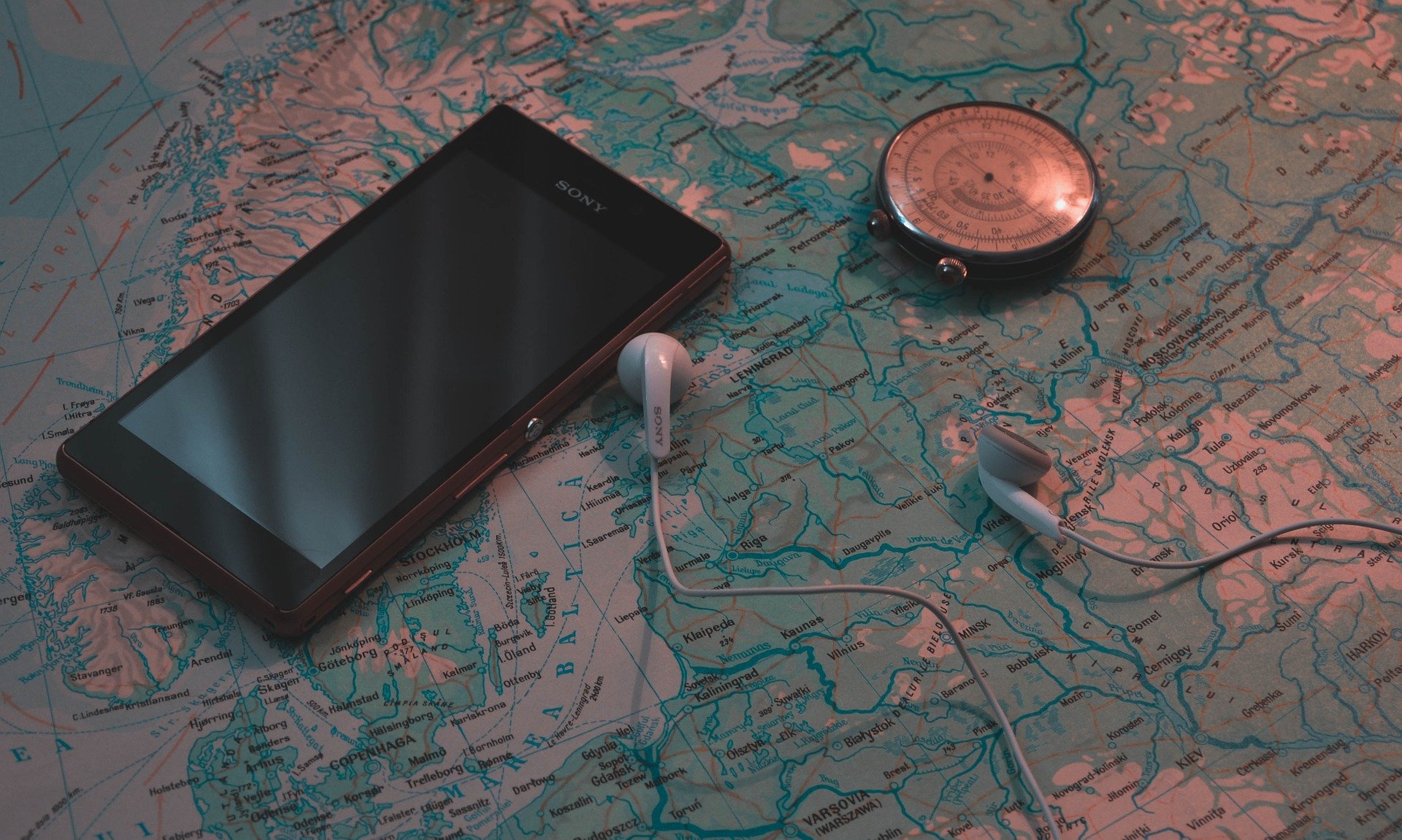 Téléphone posé sur une carte du monde avec des écouteurs et une boussole